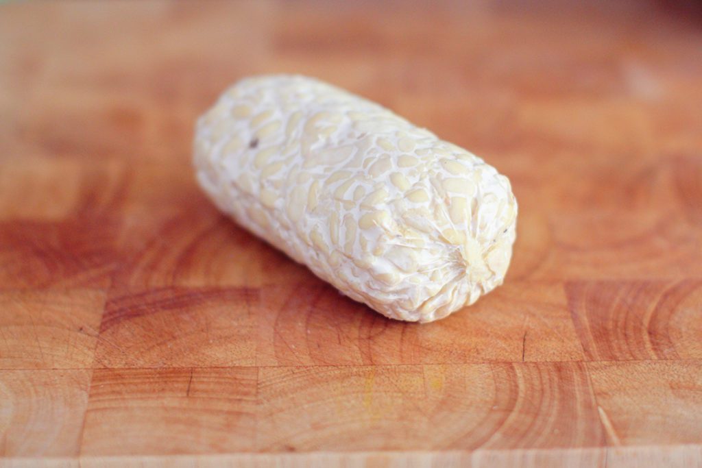 Rohes Tempeh als proteinreicher, veganer Snack auf Holzbrett