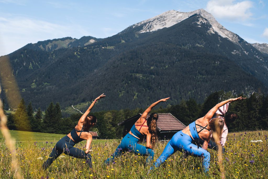 Frauen machen vor Bergkulisse Yoga