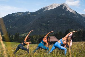 Frauen machen vor Bergkulisse Yoga