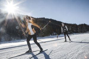 Frau beim Skating auf der Loipe vor dem Trainer