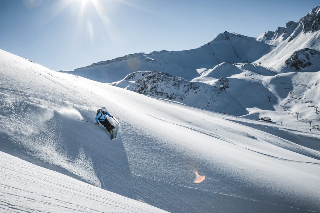 Freeriderin in blauer Jacke in Tiefschnee abseits der Piste