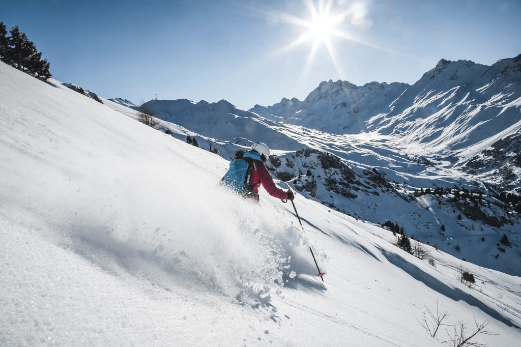 Skifahrerin in der Sonne auf der Abfahrt im Pulverschnee