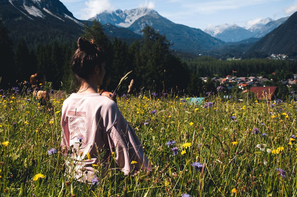 Frau sitzt auf Wildblumenwiese und meditiert